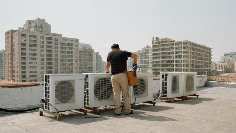 Technician testing an outdoor AC condenser with a multimeter on a rooftop